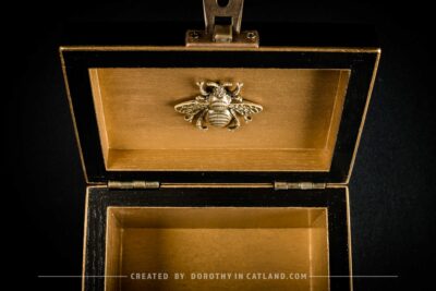 Golden interior of black jewellery box with a detailed golden metal bee ornament
