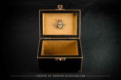 Golden interior of black jewellery box with a detailed golden metal bee ornament