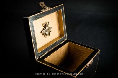Golden interior of black jewellery box with a detailed golden metal bee ornament