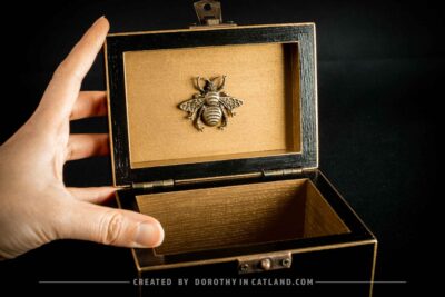 Golden interior of black jewellery box with a detailed golden metal bee ornament