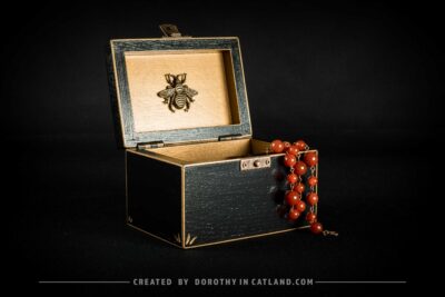 Black wooden jewellery box with a hand-painted golden flower on the lid and a golden bee inside, featuring antique bronze fittings.