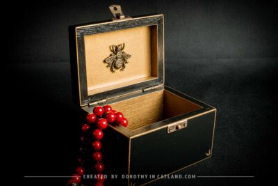 Black wooden jewellery box with a hand-painted golden flower on the lid and a golden bee inside, featuring antique bronze fittings.