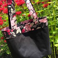 Reversible black cotton tote bag with dark pink embroidered butterfly and floral fabric details
