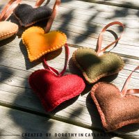 Autumn felt heart ornaments in six warm shades displayed on fabric