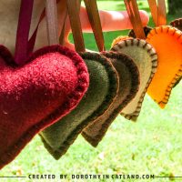 Six handmade felt heart ornaments in autumn colors hanging in warm sunlight